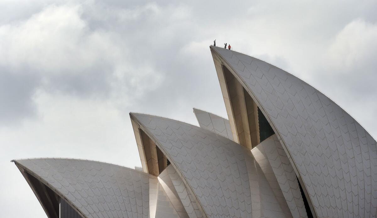 People stand on top of one of the sails that make up Jørn Utzon's Sydney Opera House in February.