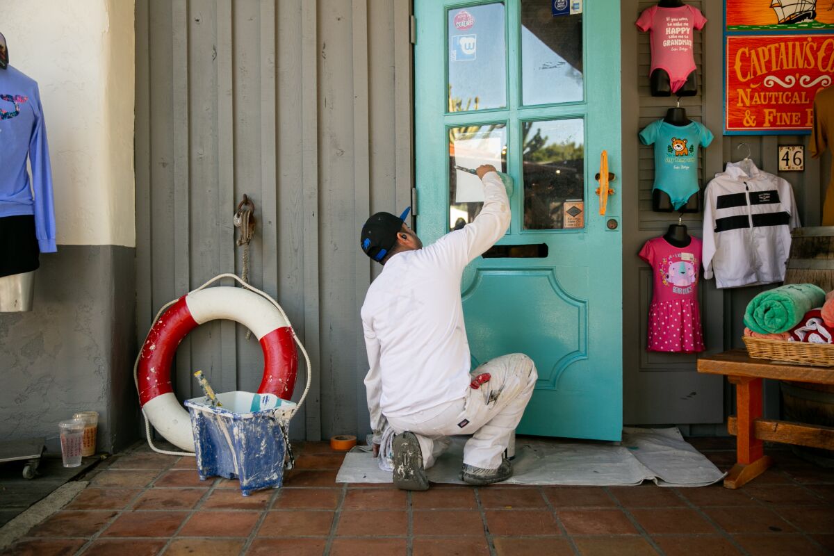 A contractor paints the door outside of a store in Seaport Village on Nov. 26, 2019 as part of a recent renovation project.