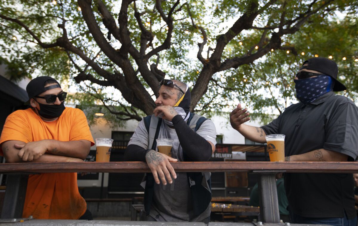 Three men enjoy a beer outside Grand Central Market in Los Angeles.