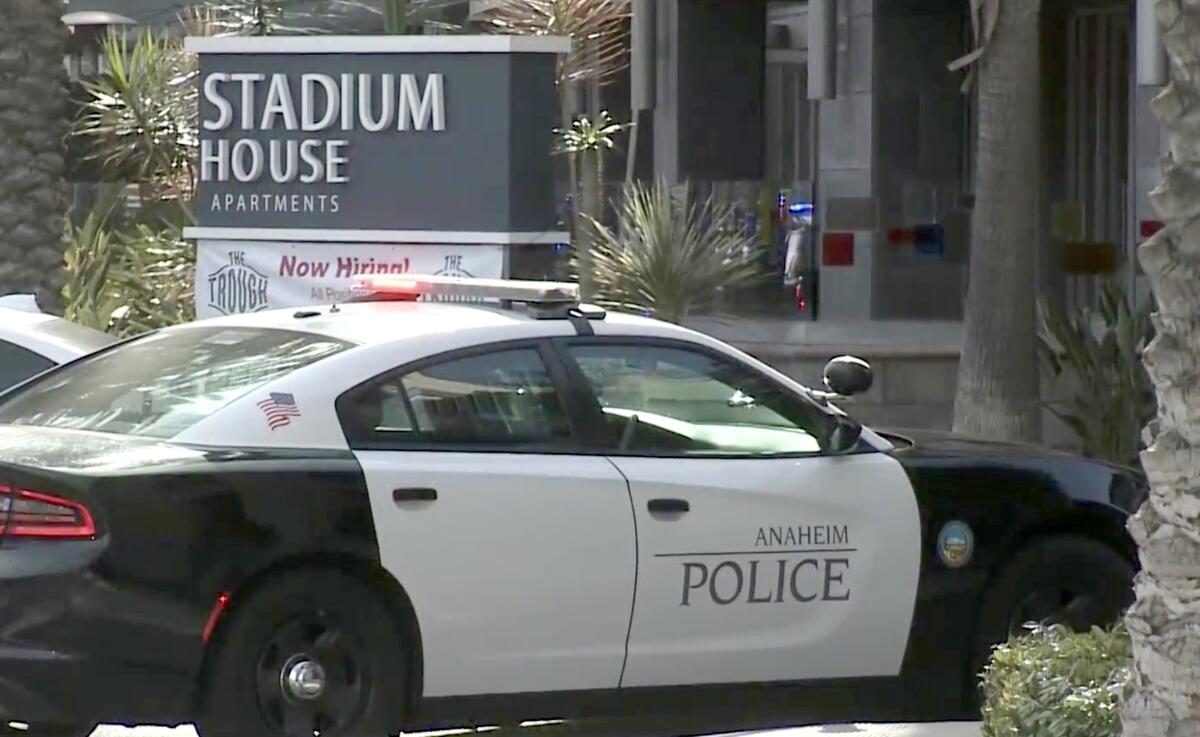 A police car sits beside a sign that reads "Stadium House Apartments"