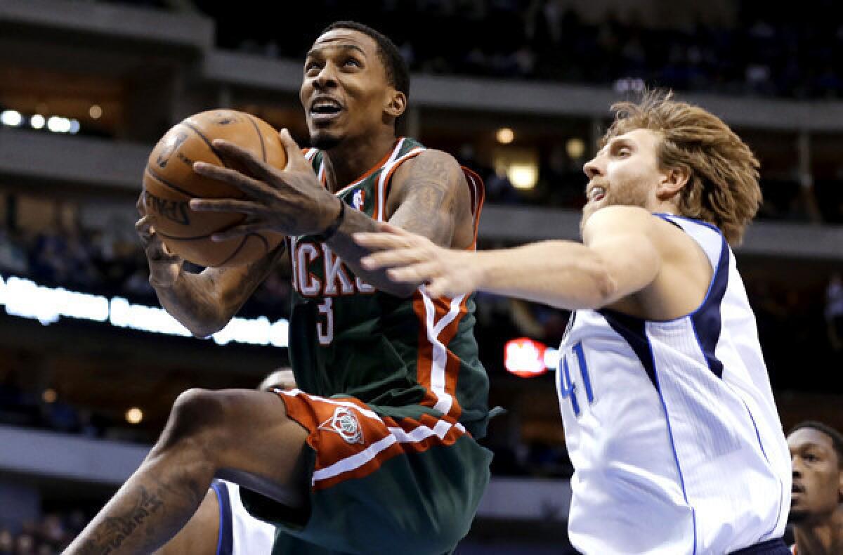 Milwaukee Bucks point guard Brandon Jennings gets past Mavericks power forward Dirk Nowitzki for a layup in a game at Dallas.