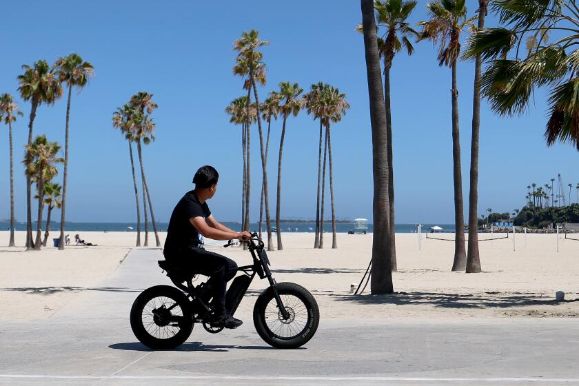 Long Beach, CA - June 9: A person rides an E-bike on the bike path in Long Beach Tuesday, June 9, 2026. E-bikes have surged in popularity across the country, especially among kids and teens, and that increase has been met with a wide array of models with different specifications and abilities. According to law enforcement officials who have worked on cases involving e-bikes, many of the models being gifted to kids and teens and bought from brick-and-mortar and online retailers are more akin to motorcycles than bicycles and can reach dangerous speeds in seconds. (Allen J. Schaben / Los Angeles Times)