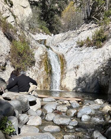 A hiker next to a waterfall at Switzer Falls.