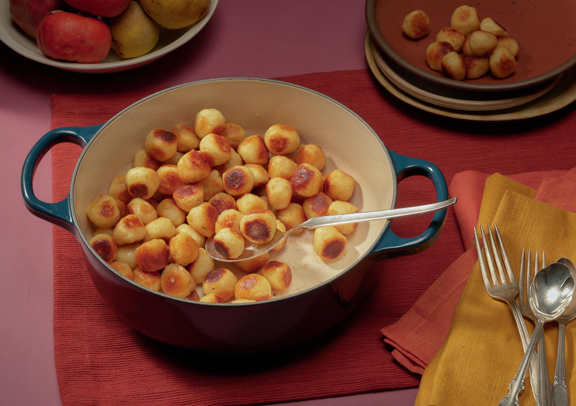 A dutch oven filled with ping-pong-sized potato balls 