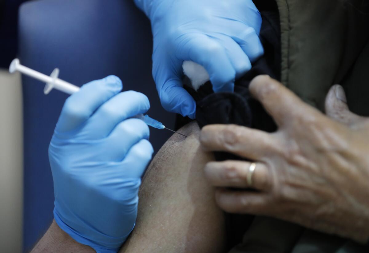 A nurse gives a shot to the shoulder of a person.