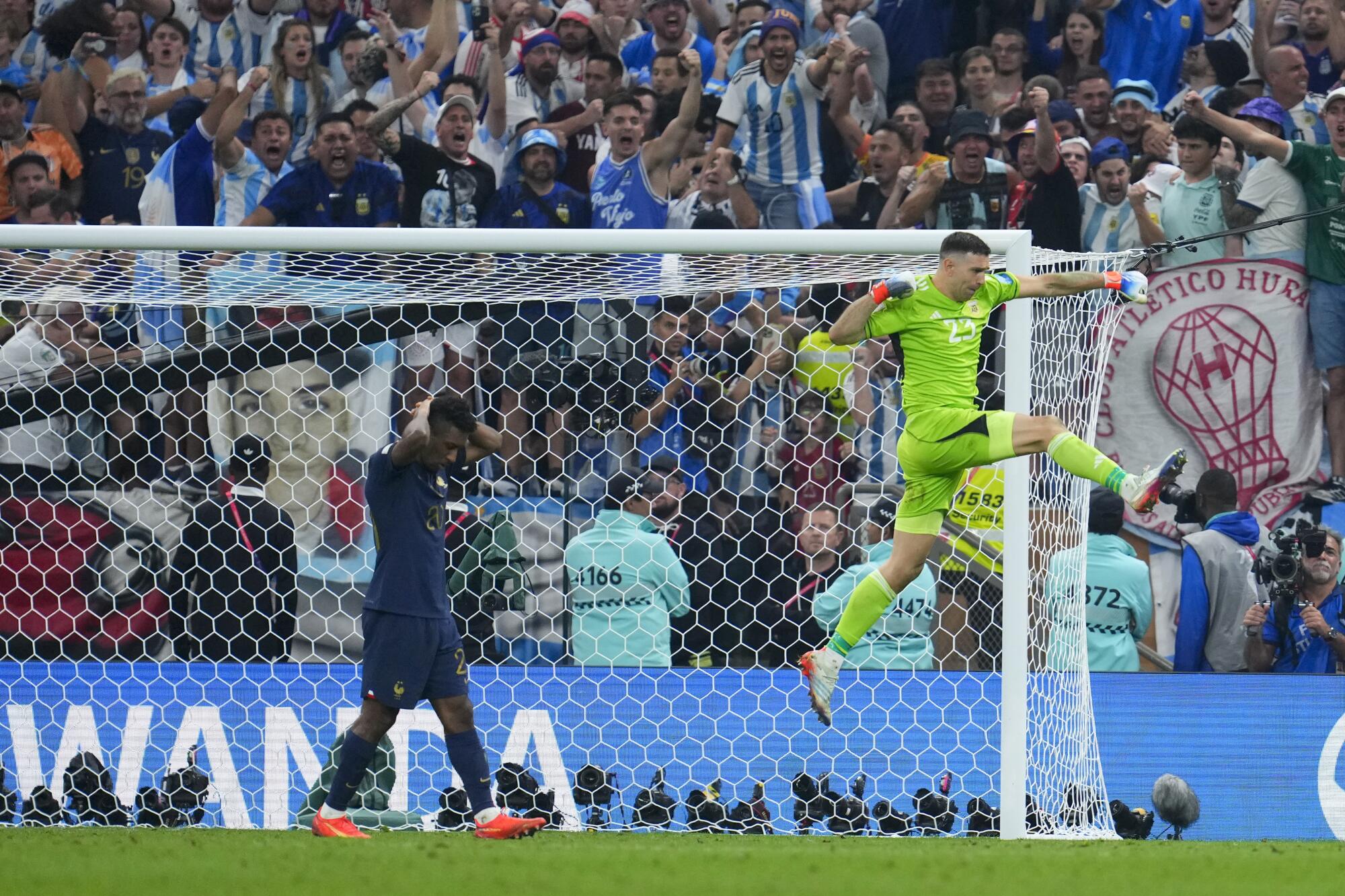 Argentina's goalkeeper Emiliano Martinez celebrates blocking a shot from France's Kingsley Coman in a penalty shootout.