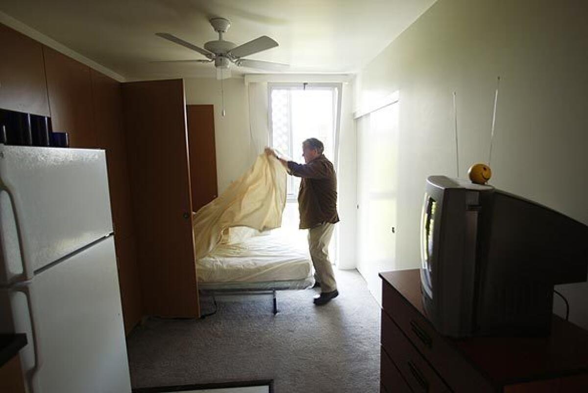 A formerly homeless man makes his bed in a Santa Monica studio apartment