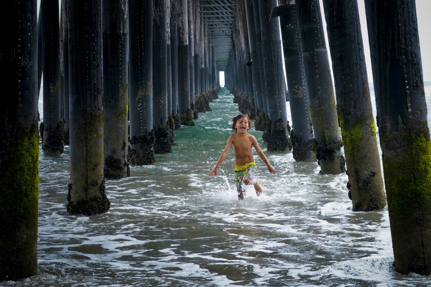 The gray weather at Oceanside Pier didn’t dampen Maddox Kroll's desire to run in the surf underneath the pier.