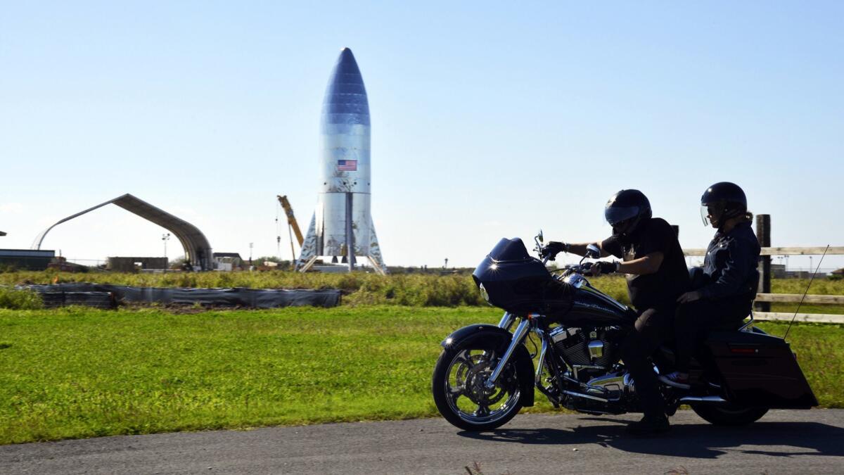 A motorcyclist rides near the SpaceX prototype Starship hopper on Jan. 12 at the Boca Chica Beach site in Texas. SpaceX test-fired a version of the engine that will power its Starship Mars spaceship.