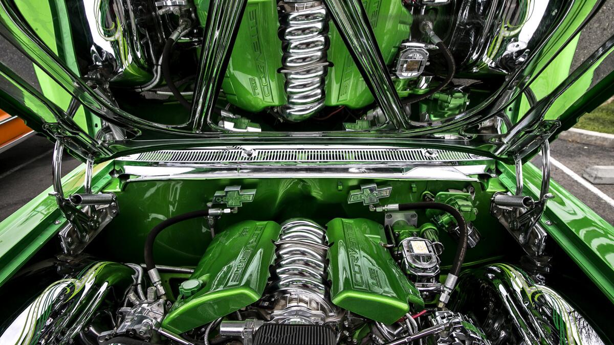 A mirrored hood reflects a finely detailed Corvette LS engine inside a 1963 Impala at a meeting of the Ultimate Riders Car Club at Fairmount Park.