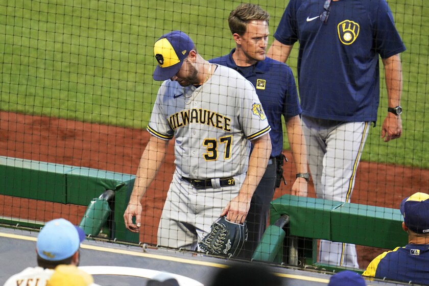 Milwaukee Brewers starting pitcher Adrian Houser (37) heads to the locker room with a trainer during the third inning of the team's baseball game against the Pittsburgh Pirates in Pittsburgh, Thursday, June 30, 2022. (AP Photo/Gene J. Puskar)