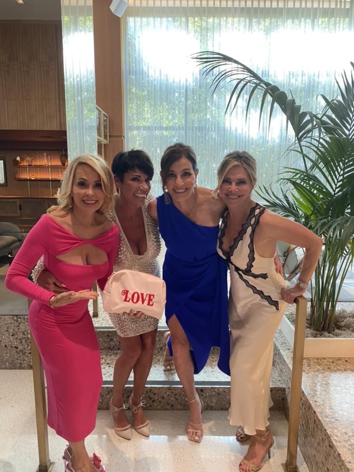 April Kirkwood holds a bag that says love and stands next to Susan Noles, Kathy Swarts and Nancy Holkower in front of stairs.