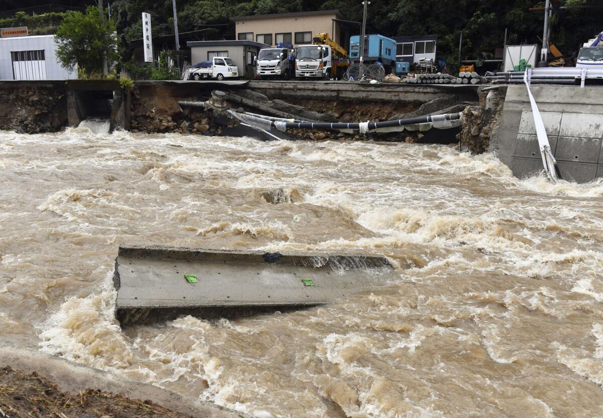 A road is damaged by the swollen Suzuhari river in heavy rain in Hiroshima, western Japan, Friday, Aug. 13, 2021. Torrential rain pounding southwestern Japan has triggered a mudslide and swallowed four people in Nagasaki and threatened the region with the risk of floods and more landslides, officials said Friday.(Kyodo News via AP)