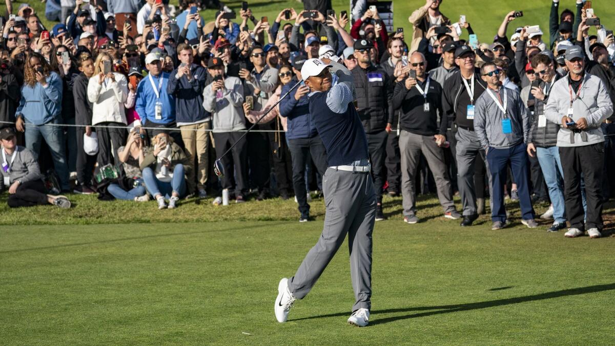 A large gallery follows Tiger Woods as he hits his tee shot on the 10th hole during his third round of the Genesis Open at Riviera Country Club on Saturday.