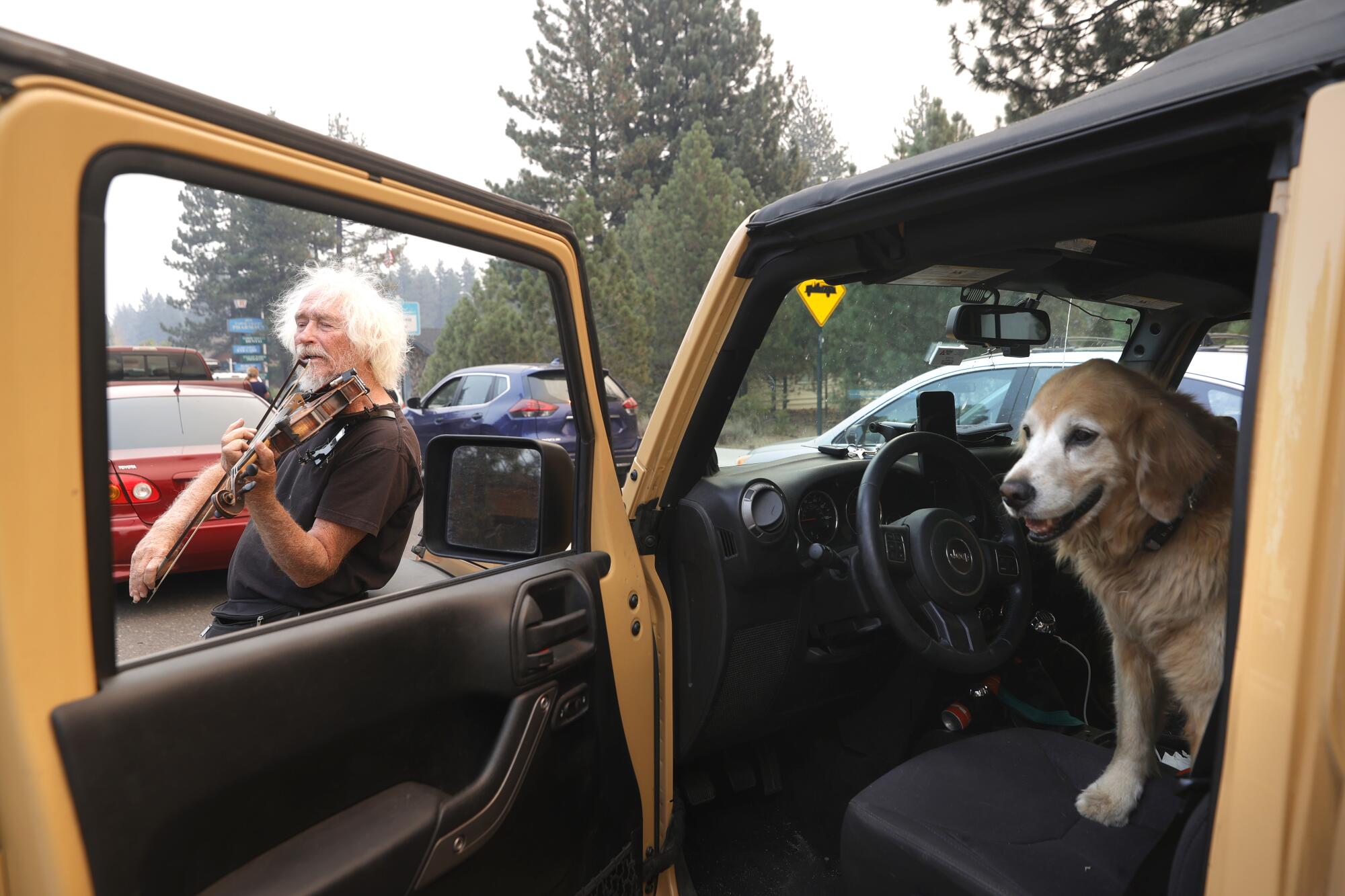 Evacuee Mel Smothers plays the violin as he waits in a miles-long traffic jam on Highway 50