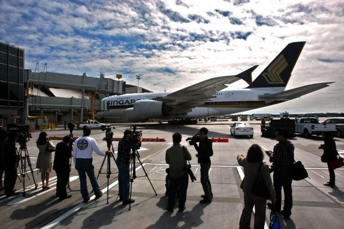 Members of the media watch as a Singapore Airlines A-380 arrives at Gate 134 of the new north concourse of the Tom Bradley International Terminal.