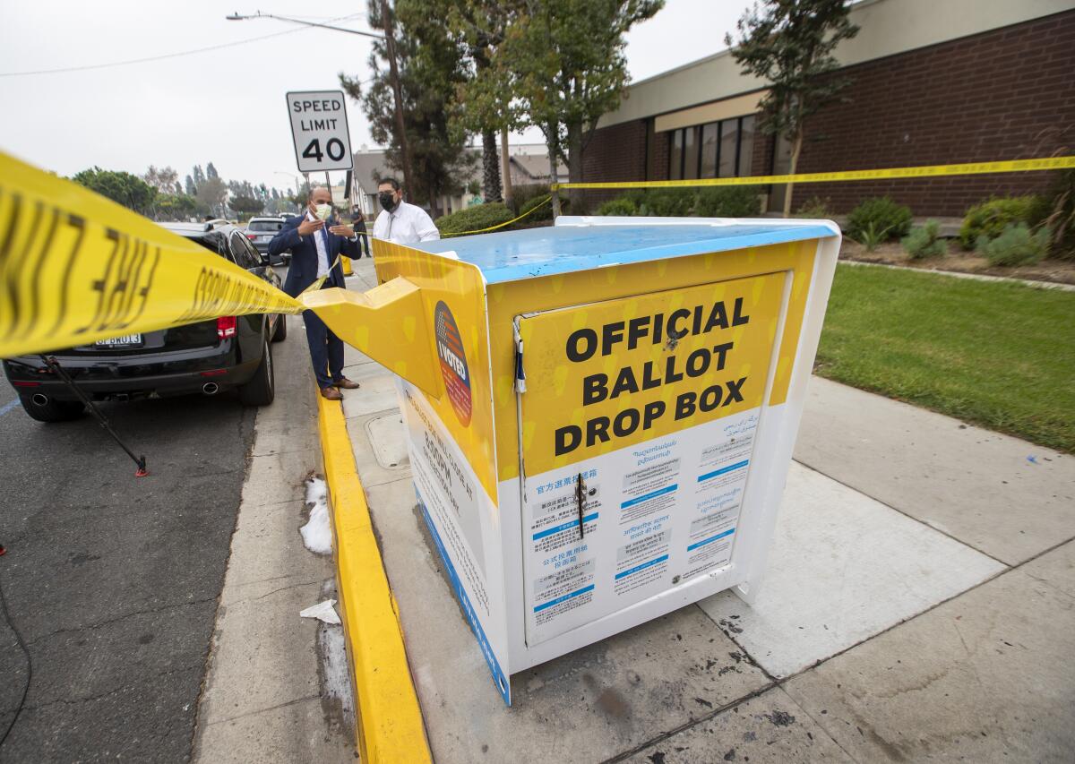 Officials in Baldwin Park inspect the fire-damaged ballot drop box on Oct. 19. 