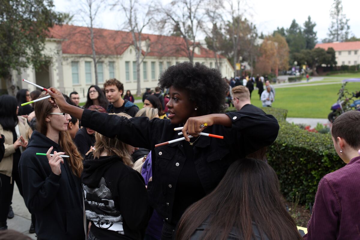 Journee Bradford, president of Whittier College's Black Student Assn., hands out markers for people to sign a banner during a commemoration for Martin Luther King Jr. on campus on Jan. 20.