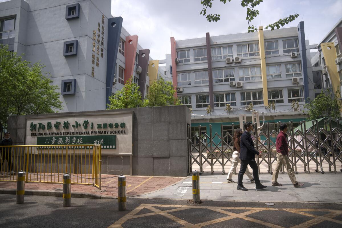 People walk past the gates of a closed primary school in Beijing.