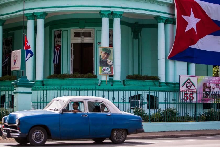 A Cuban flag flies at half staff, left, and a picture of former President Fidel Castro adorns the headquarters of the Committees for the Defense of the Revolution in Havana on Nov. 26, 2016.