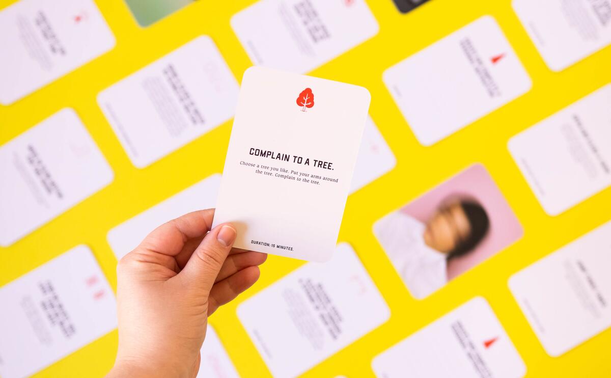 Close-up of a hand holding a card with the words "complain to a tree." 