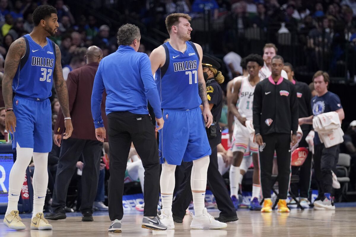 Dallas Mavericks' Marquese Chriss and a member of the staff check on guard Luka Doncic (77) who suffered an unknown lower leg injury in the second half of an NBA basketball game against the San Antonio Spurs, Sunday, April 10, 2022, in Dallas. (AP Photo/Tony Gutierrez)