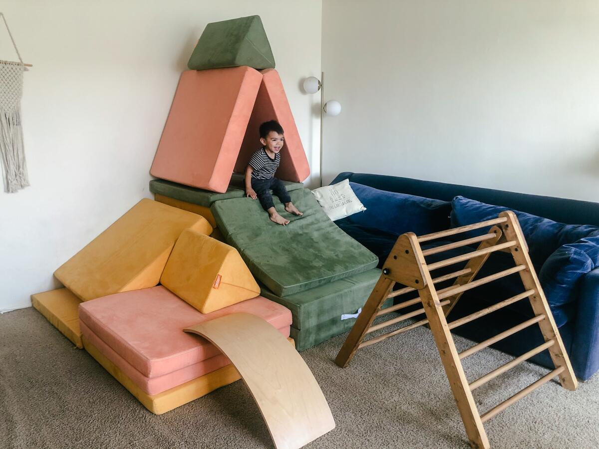 Cruz Garcia playing with Nugget couches in his Long Beach home.