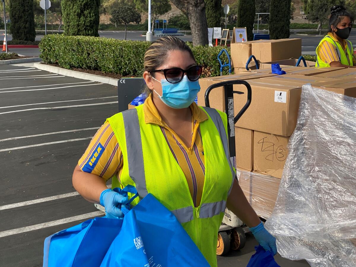 Vanessa Pasillas, a loyalty manager for IKEA in Costa Mesa, carries goods during a July 2020 giveaway event.
