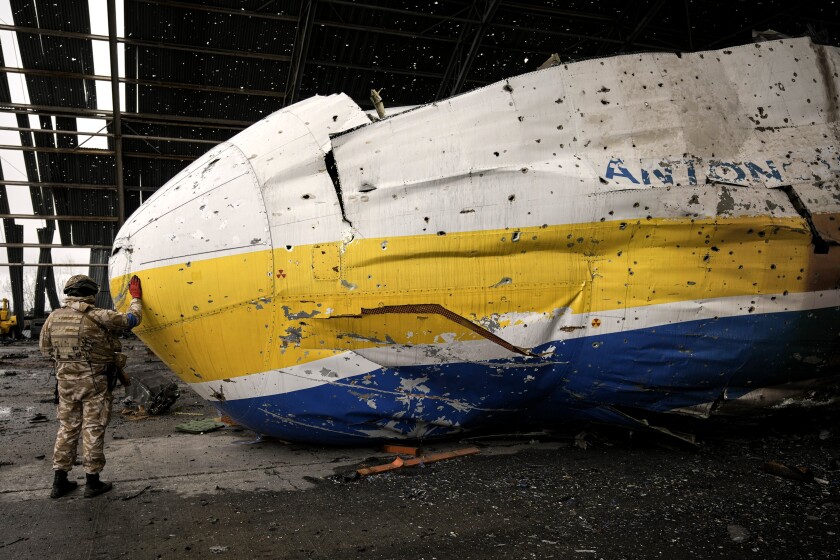 A Ukrainian serviceman touches the nose of the destroyed Antonov An-225 plane in the fighting