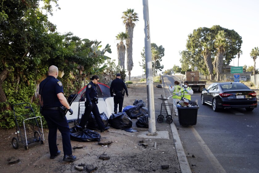 FILE - In this Sept. 25, 2017, file photo, police officers remove a tent left by the homeless in San Diego during ongoing efforts to sanitize neighborhoods to control the spread of Hepatitis A. Homeless people facing a ticket or arrest by San Diego police could have the infractions cleared if they agree to stay for 30 days in one of the city's shelters. The Union-Tribune says in a report on Sunday, Jan. 5, 2020, that the program could help stabilize lives and get people connected with services, while also allowing officers to enforce laws. (AP Photo/Gregory Bull, File)