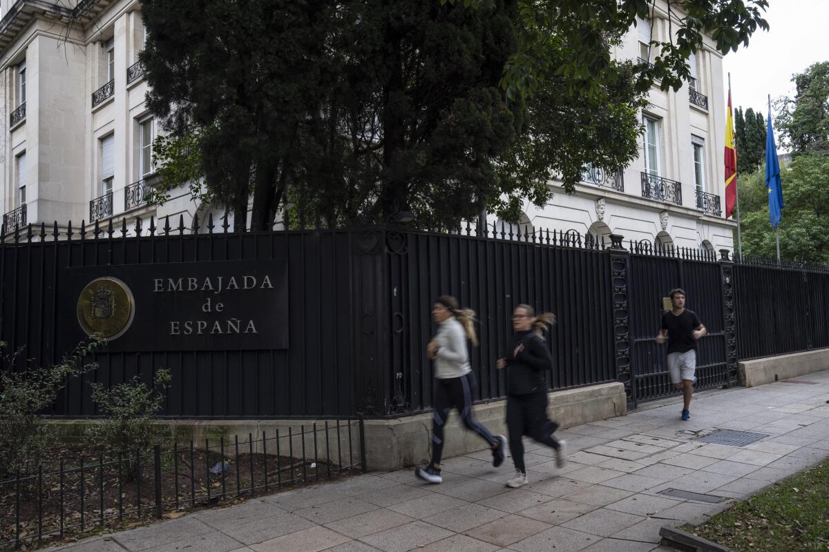 La gente pasa corriendo frente a la embajada de España en el barrio de Palermo de Buenos Aires, 
