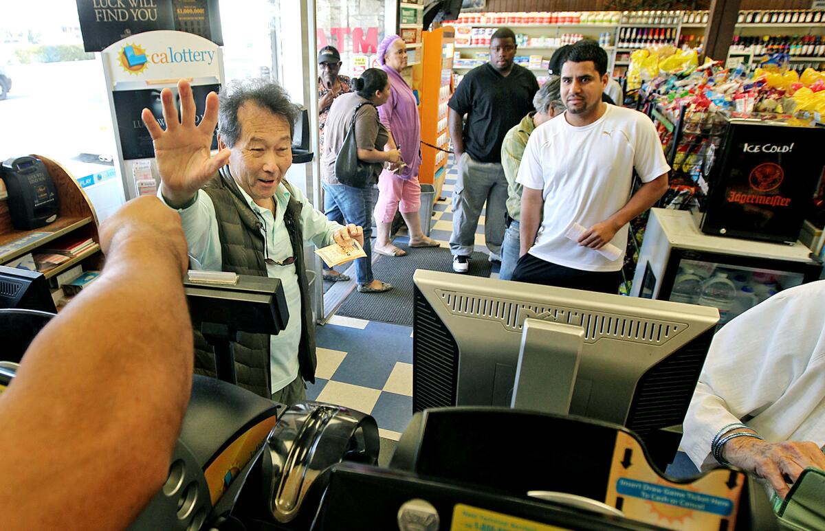 Customer Genaro Ayam-Lau, of Hawthorne, left, waves goodbye to workers at Bluebird Liquor in Hawthorne after purchasing lottery tickets on Monday