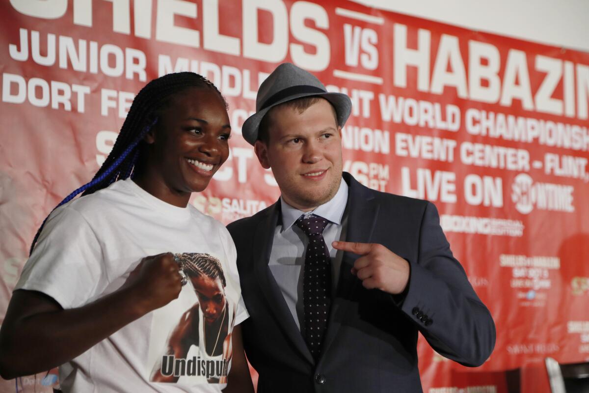 Claressa Shields poses with a fist while standing next to Dmitriy Salita, who is pointing at her.