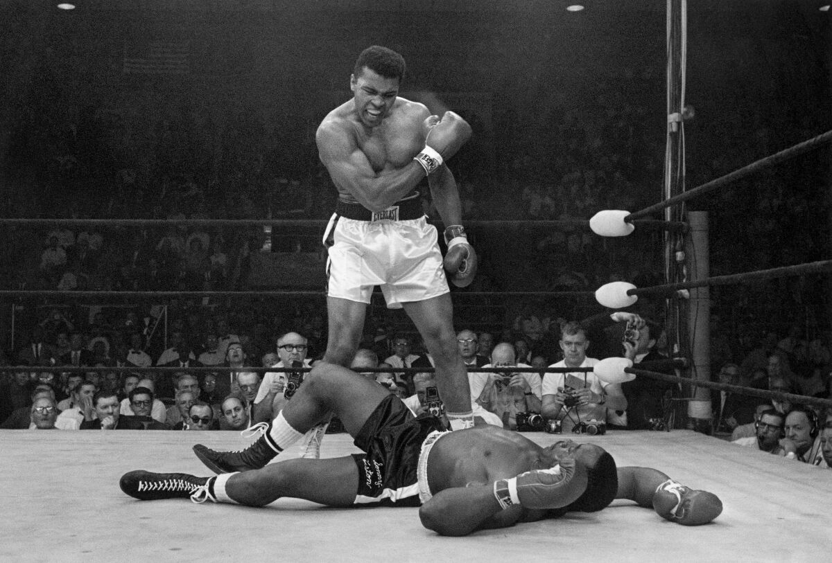 FILE - Heavyweight champion Muhammad Ali stands over fallen challenger Sonny Liston, shouting and gesturing shortly after dropping Liston with a short hard right to the jaw on May 25, 1965, in Lewiston, Maine. The legendary boxer and activist gets the Ken Burns treatment in a four-part film premiering Sept. 19 on PBS. (AP Photo/John Rooney, File)