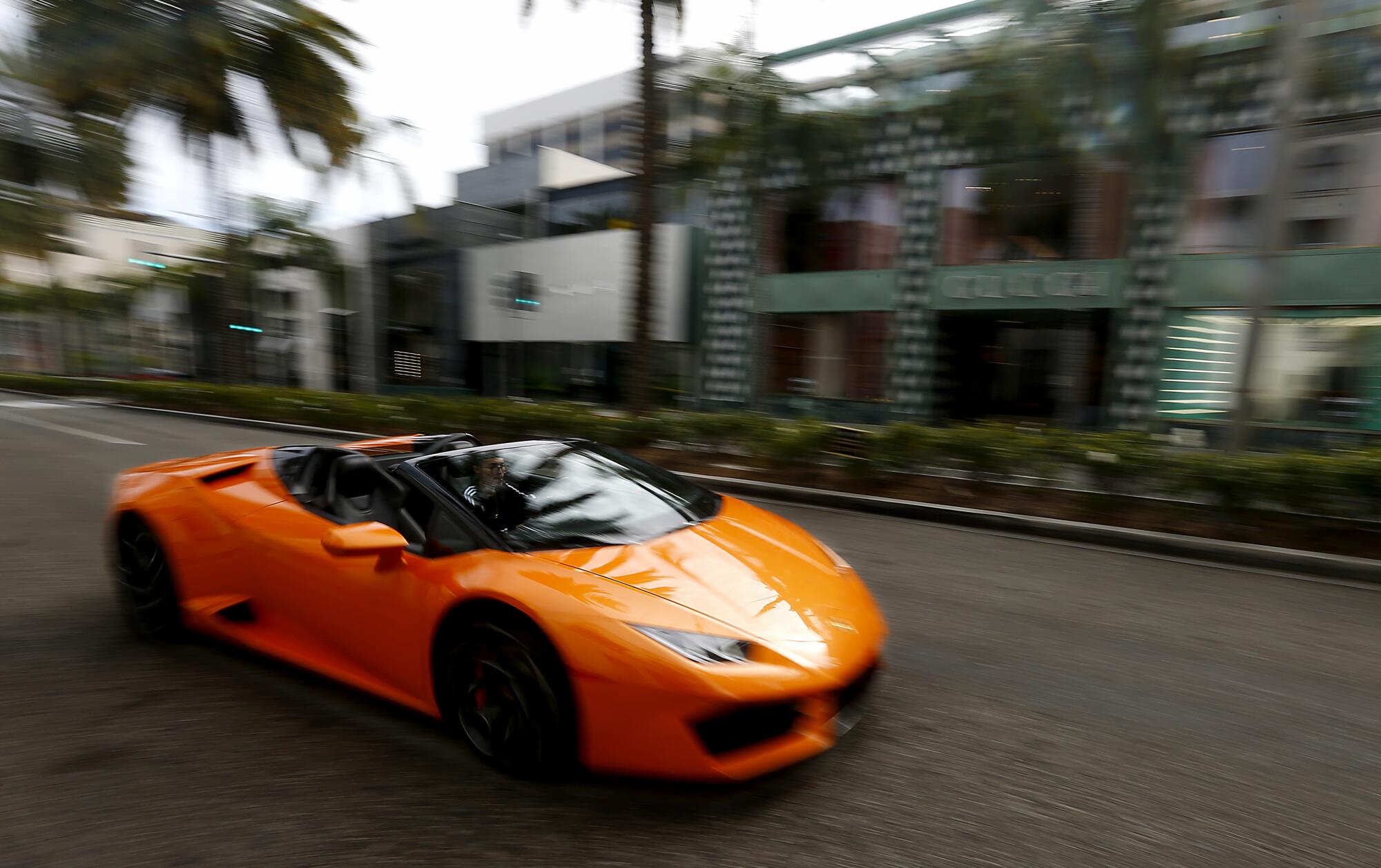 A young man drives a sports car down Rodeo Drive in Beverly Hills, where shops were closed and streets largely devoid of people and motor traffic.