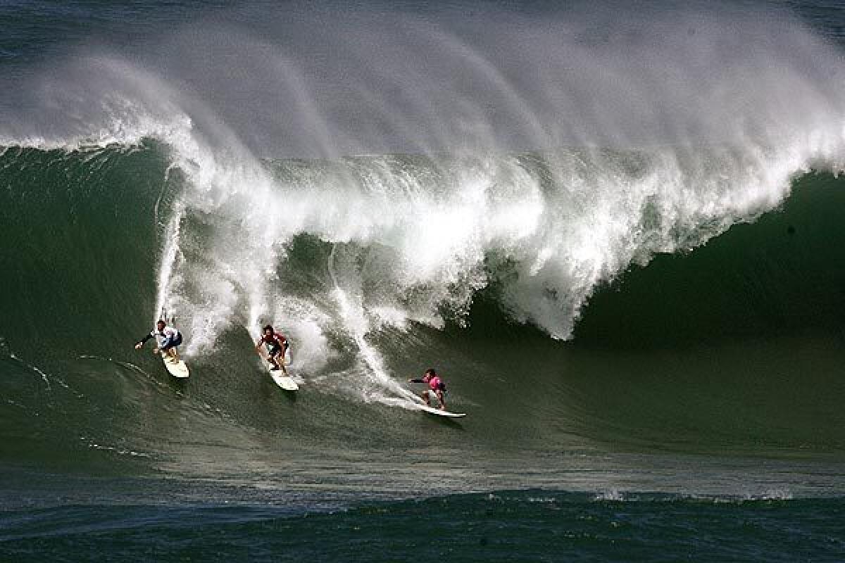Noah Johnson, Kohl Christensen and Ibon Amatrian ride a wave during a big wave surfing contest at Waimea, Hawaii.