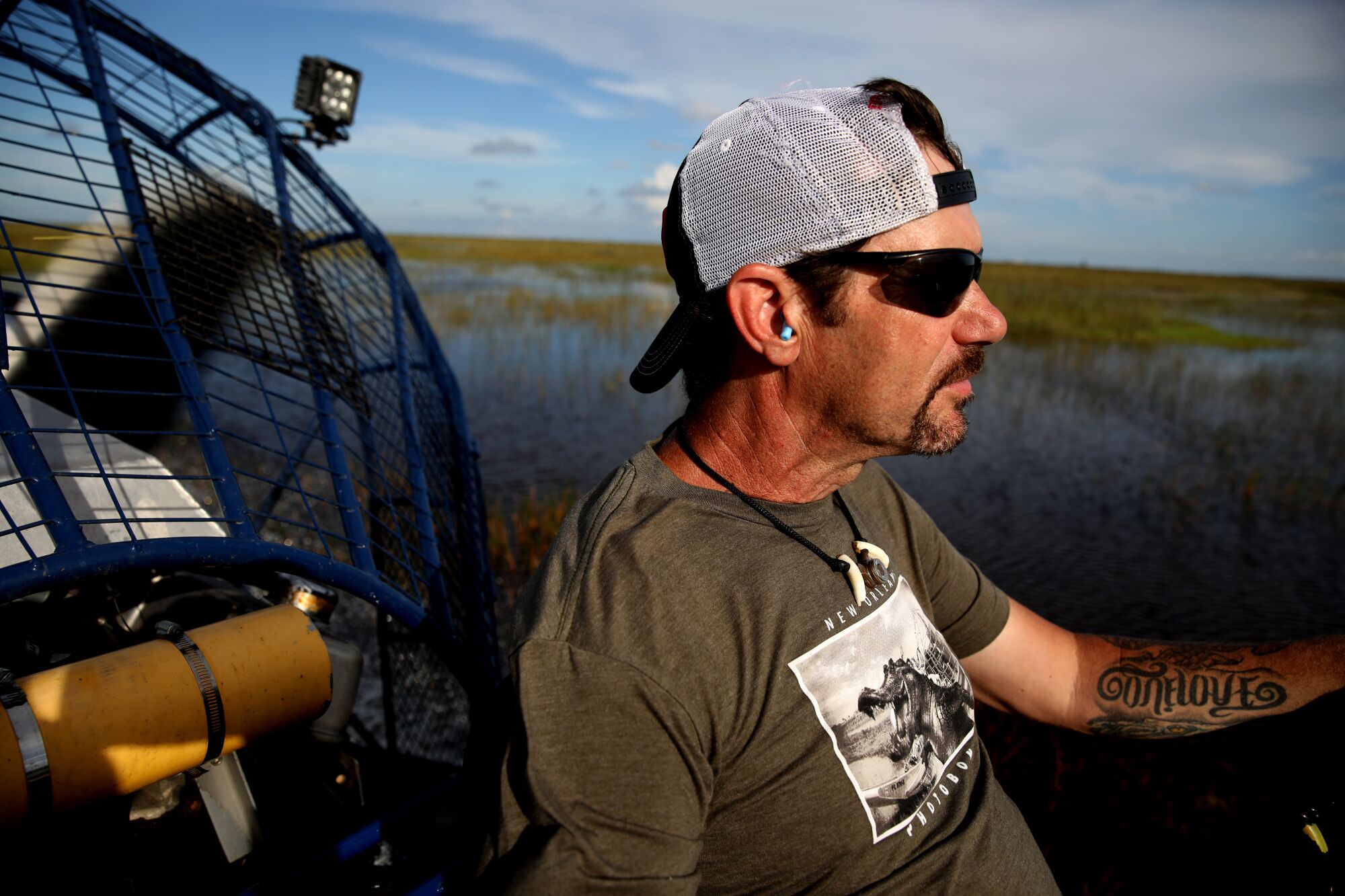 A python hunter pilots his airboat through the Everglades.