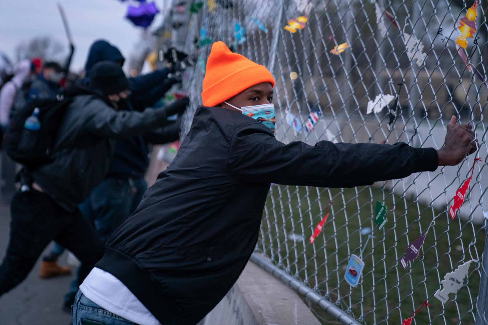 Protesters pull on a fence. 