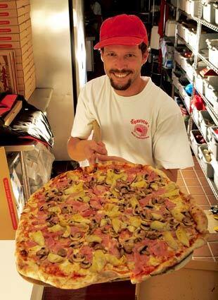 Angelo Vukelja hoists a quattro gusti (ham, mushrooms, artichokes and mozzarella) pizza at Pavich's Brick Oven Pizzeria in San Pedro.