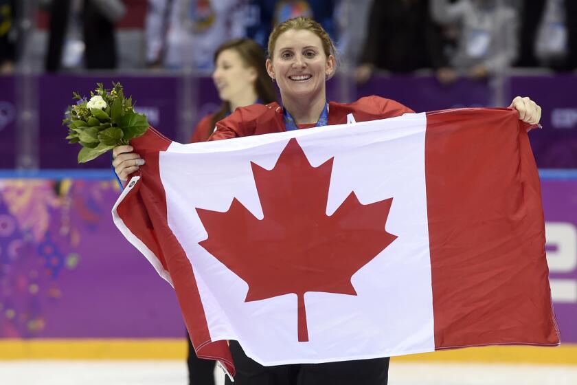 Canada's Hayley Wickenheiser #22 celebrates with the Canadian flag after beating the USA 3-2 in overtime at the Sochi Winter Olympics Friday, February 21, 2014 in Sochi. (AP Photo/Paul Chiasson, The Canadian Press)