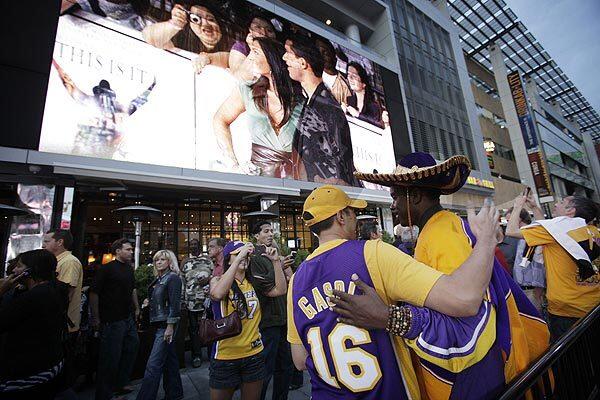 Lakers fans embrace under the big screen showing celebrities and Michael Jackson fans arriving for the premiere of "This Is It" at L.A. Live. The Lakers and Clippers opened their seasons against each other at the Staples Center the same night.