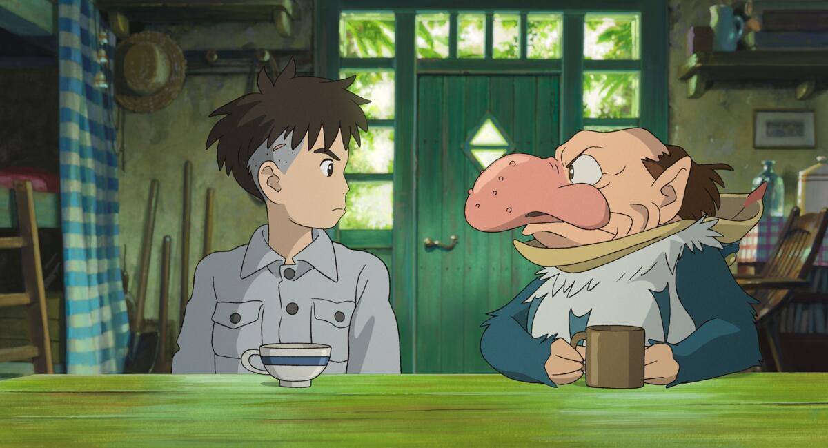 A teen boy sits at a table with a man-like creature in the animated "The Boy and the Heron." 