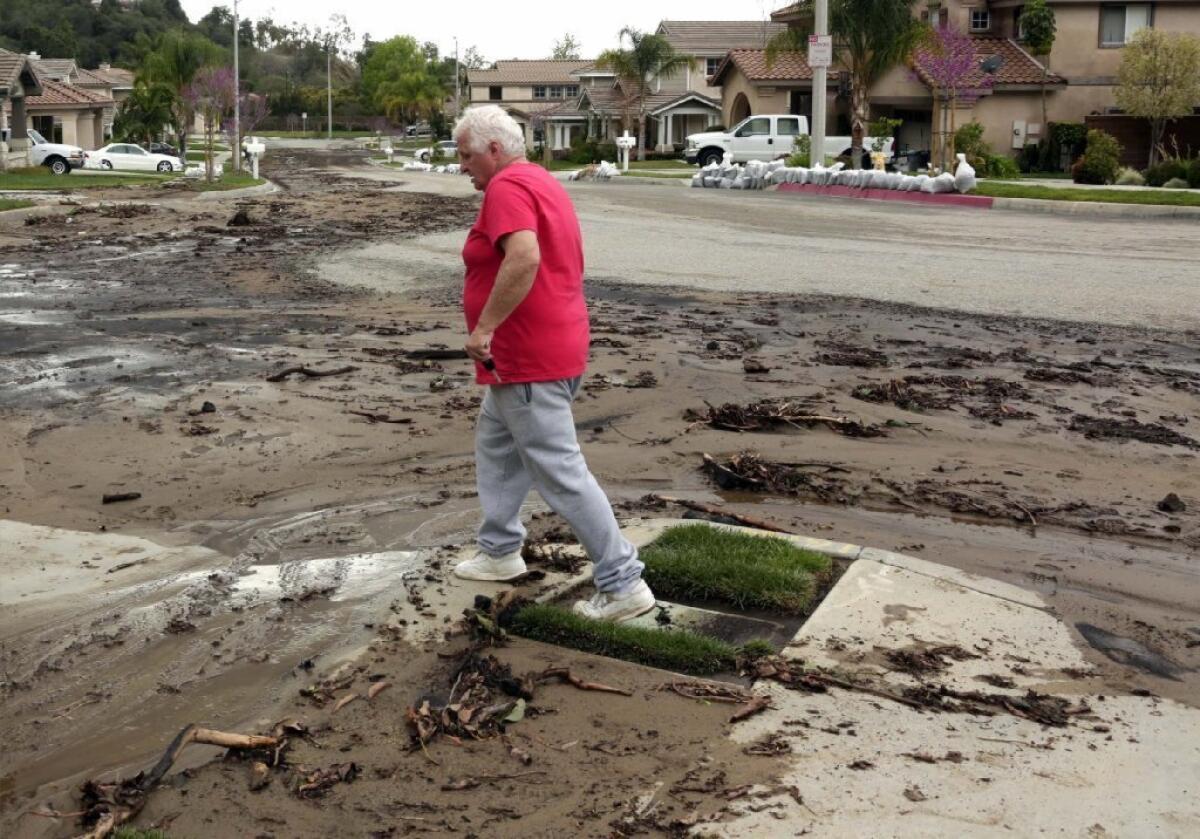 Azusa resident Ed Heinlein walks through the mud on the street in front of his home.