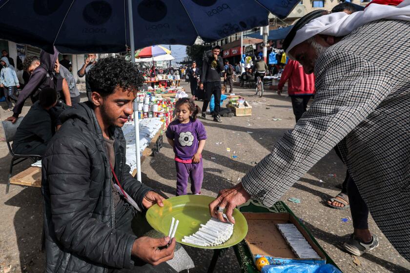 TOPSHOT - A man buys hand-rolled cigarettes from a vendor's stall along a market street in Rafah in the southern Gaza Strip on April 23, 2024 amid the ongoing conflict in the Palestinian territory between Israel and the militant group Hamas. (Photo by MOHAMMED ABED / AFP) (Photo by MOHAMMED ABED/AFP via Getty Images)