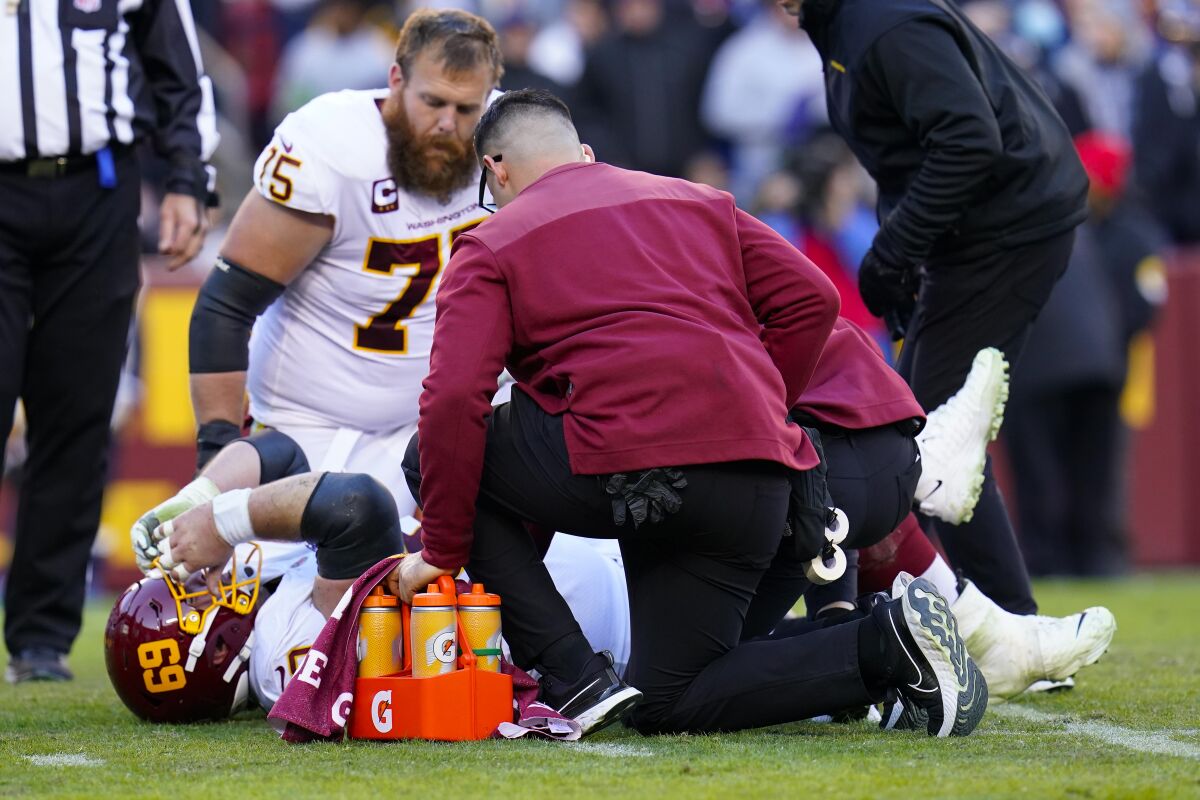 Washington Football Team center Tyler Larsen (69) is attended to by members of the medical team after being injured following a play during the second half of an NFL football game against the Dallas Cowboys, Sunday, Dec. 12, 2021, in Landover, Md. (AP Photo/Julio Cortez)