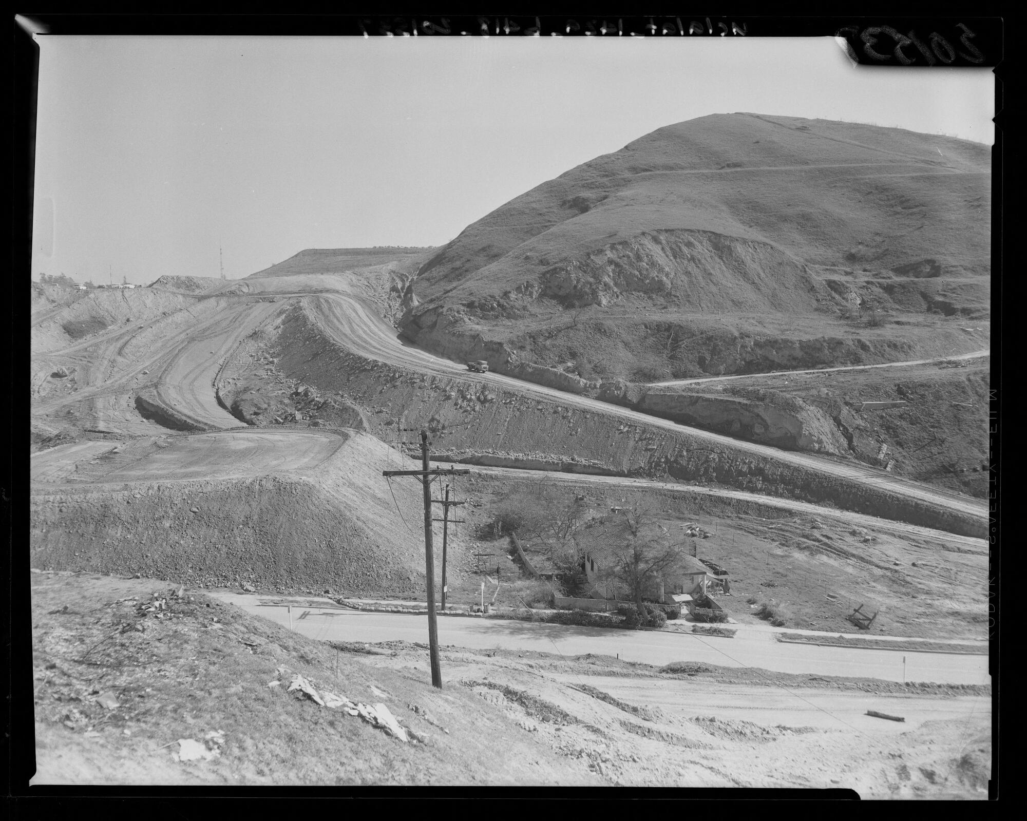 A single house surrounded and cut off by land grading in preparation for the Dodgers' Chavez Ravine ballpark.