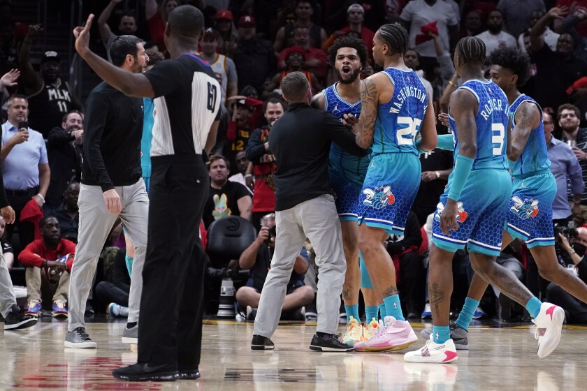 Charlotte Hornets forward Miles Bridges (0) is restrained by P.J. Washington (25) and others as he argues with an official after being charged with a foul during the second half of the team's NBA play-in basketball game against the Atlanta Hawks on Wednesday, April 13, 2022, in Atlanta. Bridges was ejected. (AP Photo/John Bazemore)