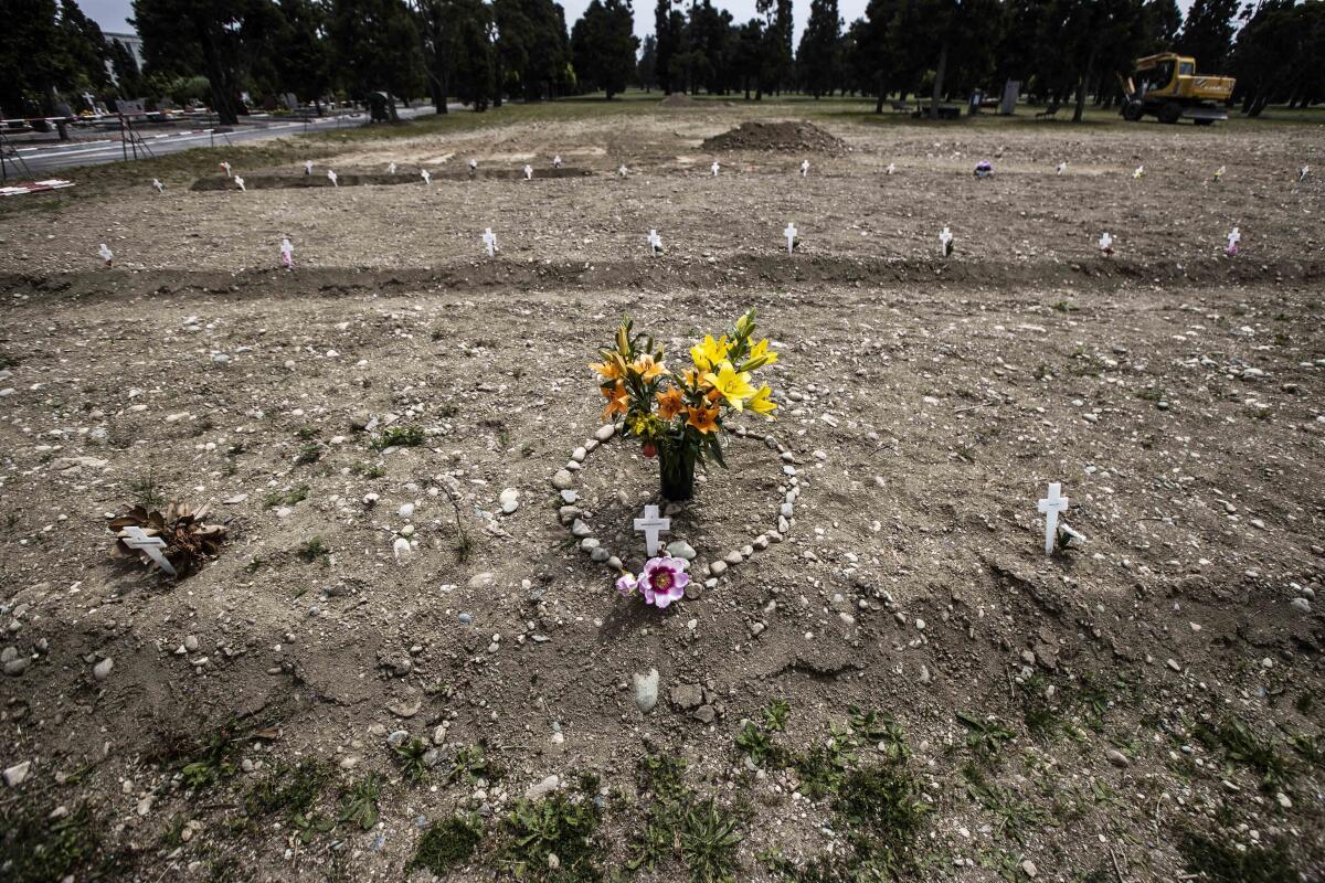 Flowers and stones placed in the shape of a heart are laid on a burial site for COVID-19 victims in Milan, Italy.