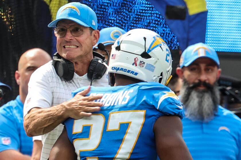 Coach Jim Harbaugh emphatically congratulates Chargers running back J.K. Dobbins.