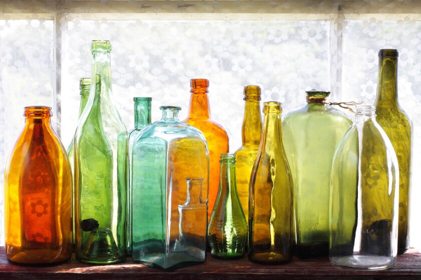 Exposição de garrafas de vidro coloridas.